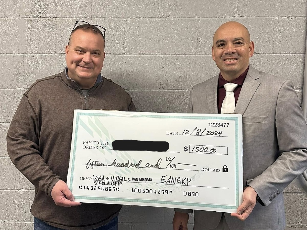 An EANGKY officer presenting an oversized scholarship check for $1,500 to a recipient